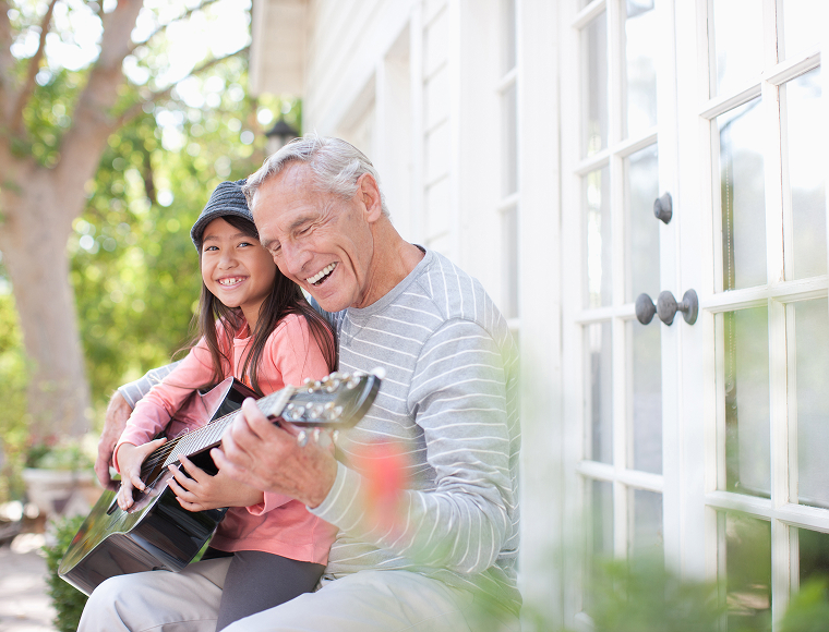 young girl playing guitar with grandfather